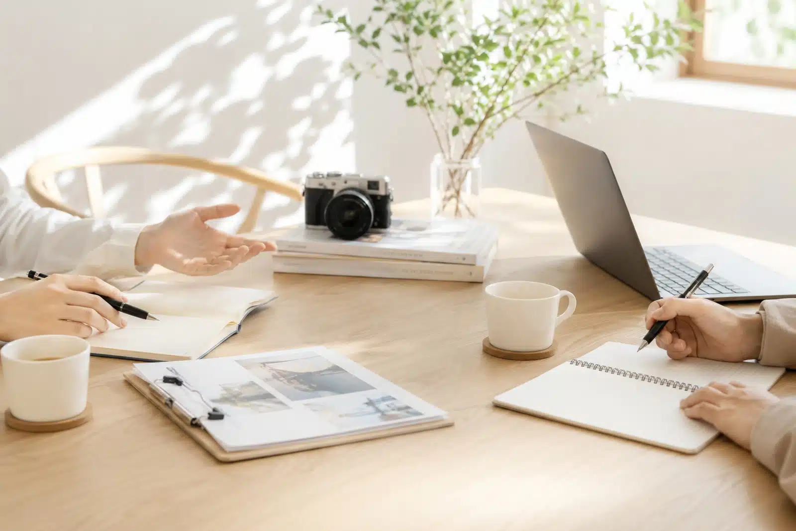 カメラとノートパソコンを囲み、写真撮影や映像制作について打ち合わせる様子